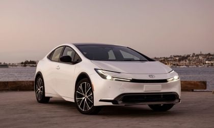 A sleek white Toyota car parked by a tranquil waterfront at sunset, showcasing modern design and elegant features.