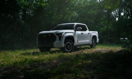 2026 Toyota Tundra in white, photographed at three-quarter front angle in a wooded setting, featuring black accents and distinctive alloy wheels.