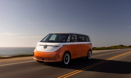 Orange and white Volkswagen ID.Buzz electric van driving on coastal highway at sunset