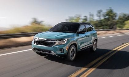 Teal 2026 Kia Seltos crossover SUV driving dynamically on highway with blurred trees and road markings in background
