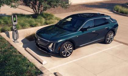 Green 2026 Cadillac Lyriq Luxury parked beside an EV charger in an overhead front three-quarter view.