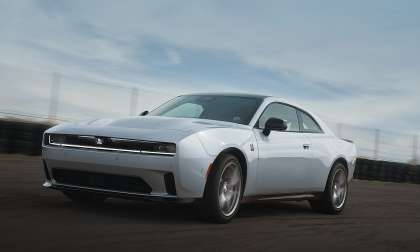 White 2026 Dodge Charger coupe driving on a racetrack in a front three-quarter action shot.