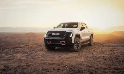 2026 GMC Sierra EV AT4 parked in a desert landscape at sunset with warm light behind it.
