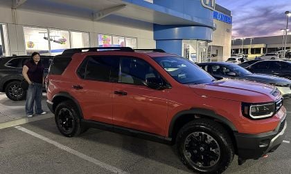 2026 Honda Passport TrailSport orange SUV parked at dealership during first look with rugged wheels and black trim
