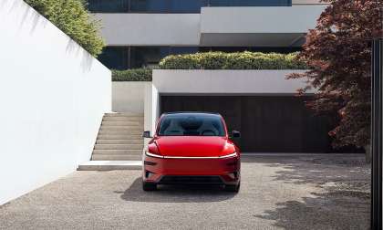 Red 2026 Tesla Model Y Performance shown from the front outside a modern home.