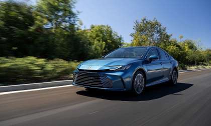 Ocean Gem 2026 Toyota Camry XLE AWD driving on a tree-lined road in a front three-quarter action view.