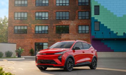 2027 Chevrolet Bolt EV red compact electric SUV front three-quarter view parked in urban setting