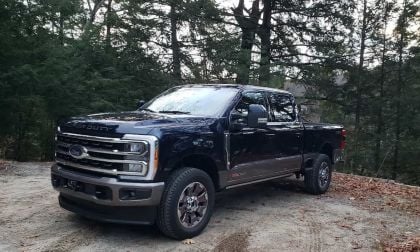 Image shows a Ford F-250 in blue and silver against a backdrop of a wooded area.