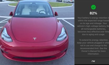 Candy red Tesla Model 3 parked head-on, sleek electric sedan with minimalist front design in parking lot