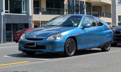 Blue Honda Insight hybrid hatchback parked in urban lot, sleek aerodynamic design with smooth metallic finish