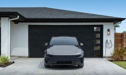 A 2026 Tesla Model Y parked in front of a modern house with a white exterior and a black garage door. The setting is clean, stylish, and contemporary.