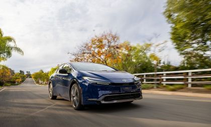 Blue Toyota Prius driving on suburban road with trees and houses