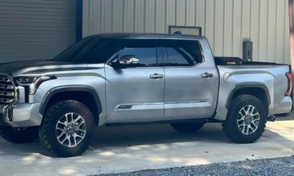 Silver 2023 Toyota Tundra with large tires parked under a metal carport. The truck has tinted windows and a modern design, conveying strength and utility.