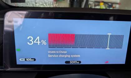 Car dashboard display showing a battery at 34% charge with a red warning bar. Text reads: "Unable to Charge, Service charging system." Odometer at 5,097 miles, range 105 miles.