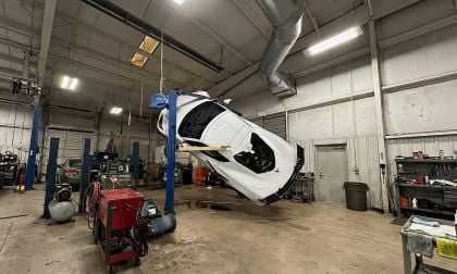 Chevrolet Corvette C8 lifted sideways on a vehicle lift inside an auto repair shop