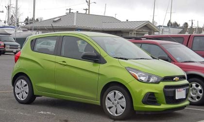 A lime green colored Chevrolet Spark sits in a parking lot.