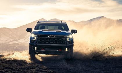 Chevrolet Silverado kicking up dust while driving through rugged desert mountain terrain at sunset
