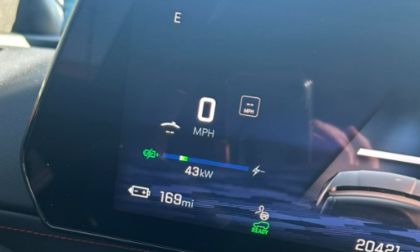 Digital instrument cluster display showing 0 MPH, 43kW power output, 165 miles of remaining range, and various indicator lights on a dark blue background.