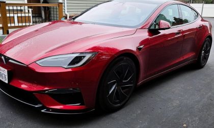 A red Tesla Model S Plaid shown from a front three-quarter angle, featuring its distinctive LED headlights and aggressive front design with black accents and wheels.