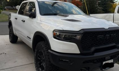 White 2025 Ram 1500 Rebel pickup truck shown featuring its distinctive wide body, hood scoop, and black trim accents.