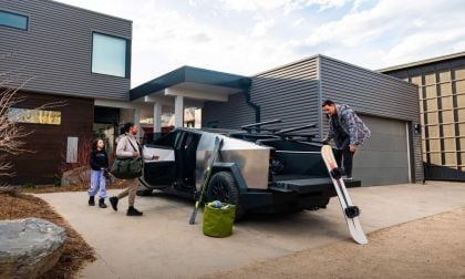A 2025 Tesla Cybertruck parked in a modern driveway, with three people loading snowboards and gear for an outdoor adventure.