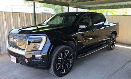 Sleek black GMC Sierra Denali pickup truck with premium wheels parked under metal carport