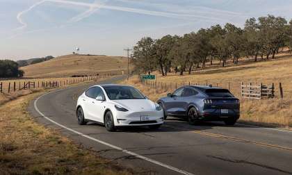 Tesla Model Y and Ford Mustang Mach-E driving in a rural area.