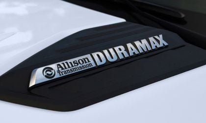 Close-up of a Chevrolet Silverado hood with "Allison Transmission" and "Duramax" in shiny silver letters on a black accent, conveying strength and durability.