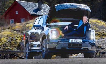 Blue Ford F-150 Lightning with a man sitting in the frunk