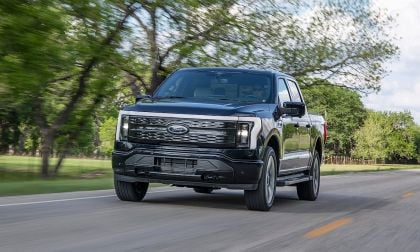 Ford F150 Lightning Platinum electric pickup truck driving on a road through trees