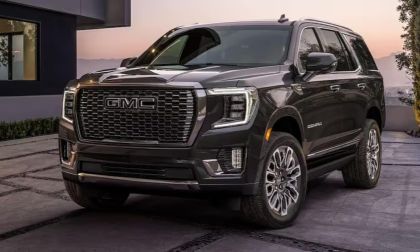 Black and silver 2025 GMC Yukon Denali parked in a desert landscape with rugged terrain and canyon cliffs.
