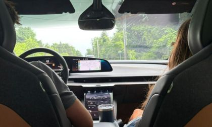 Two passengers in the front of a Lucid Air, engaged in conversation while driving on the road