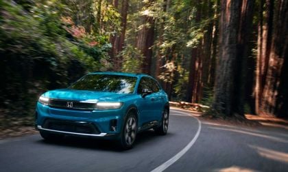 A light blue Honda Prologue travels down windy, wooded road