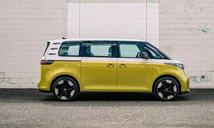 A yellow Volkswagon ID Buzz sits parked and readym with a white brick wall in the background