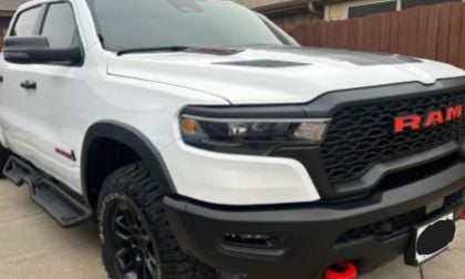 White Ram 1500 pickup truck shown from a front three-quarter angle, featuring its distinctive black mesh grille with red Ram lettering and aggressive off-road bumper design.