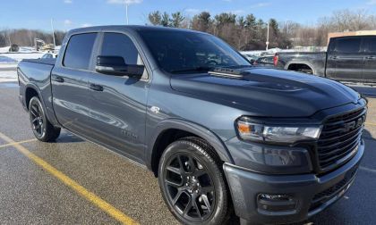 James' gray/charcoal 2026 Ram 1500 pickup truck shown from the front three-quarter angle, featuring black wheels and a blacked-out grille in a parking lot setting.