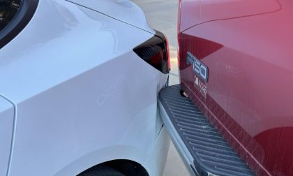 Close-up detail shot of a Ford F-150 truck's rear being dented in by a 2025 Tesla Model 3.