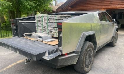 Tesla Cybertruck with open tailgate, loaded with stacked stone pavers in residential setting