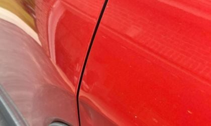 Glossy red car panel with reflective surface and door seam close-up