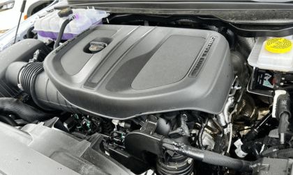 Close-up of a new Ram 1500's engine compartment, featuring a prominent engine cover marked "TURBO" and visible components. The scene conveys precision and modern engineering.