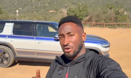 Marques Brownlee points to the camouflaged Rivian R2