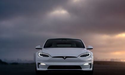 Front view of a 2025 white Tesla Model S against a dramatic cloudy sky, showcasing its modern design and iconic logo.