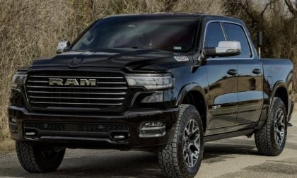 Nolan's black Ram 1500 pickup truck is parked on a deserted road with leafless trees in the background. The vehicle looks rugged and ready for off-road adventures.