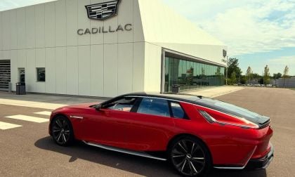 A red 2026 Cadillac Celestiq parked outside a modern dealership showcasing the brand's logo against a clear sky.