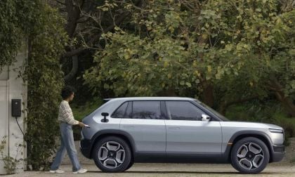 Rivian R2 Side profile, gray with one man walking towards it