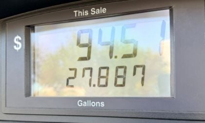 Gas pump display showing $94.51 for 27.887 gallons. The screen is framed in gray and the background appears blurred.