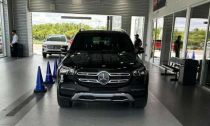 Ry's Mercedes-Benz GLE 350 is parked in a showroom with a gray tiled floor. Blue cones are placed in front. A white SUV is visible in the background.