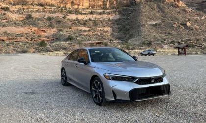 A silver Honda Civic parked on gravel with red rock formations in the background, showcasing a scenic desert landscape.