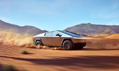 Futuristic and metallic looking Tesla Cybertruck driving through a desert landscape, kicking up sand. Mountains under clear sky in the background, conveying speed and adventure.