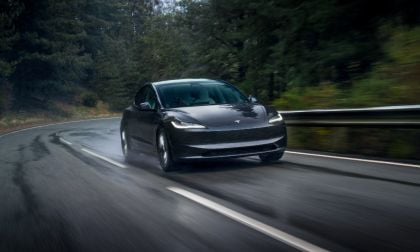 Black Tesla Model 3 speeding on wet forest road with motion blur and dynamic handling